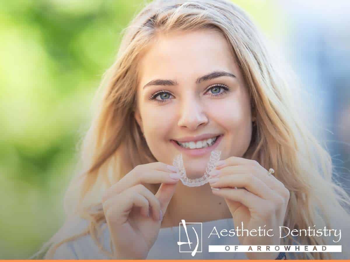 Young woman holding a clear removable aligner