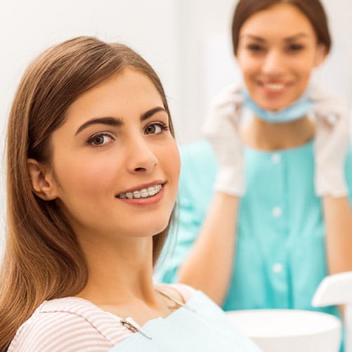 Female patient smiling and showing off her clear braces